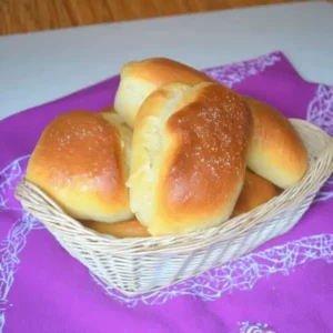 Panini all’olio dorati in cestino di vimini su tovaglia viola