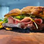 Panino con mortadella servito su tagliere di legno