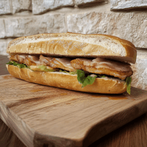Panino con porchetta su tagliere di legno, visto da vicino